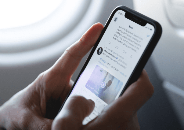 A person browsing Twitter on their phone on an airplane