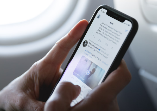 A person browsing Twitter on their phone on an airplane
